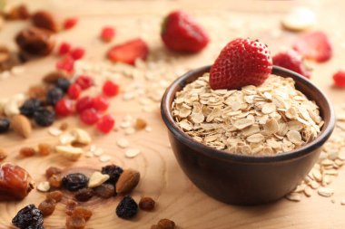 Yulaf ezmesi gevreği, çilek ve ahşap masa üzerinde kurutulmuş meyve kase