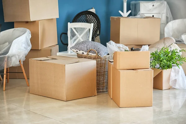 Carton boxes and interior items on floor in room. Moving house concept