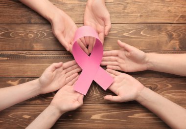 Pembe kurdele ahşap arka plan üzerinde tutan eller. Meme kanseri bilinçlendirme kavramı