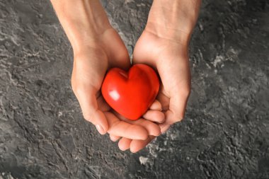 Kadının karanlık dokulu arka plan üzerinde kırmızı kalpli eller