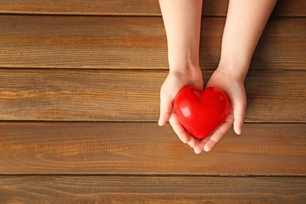 Ahşap Arka Plan Üzerinde Kırmızı Kalpli Çocuk Elleri — Stok fotoğraf