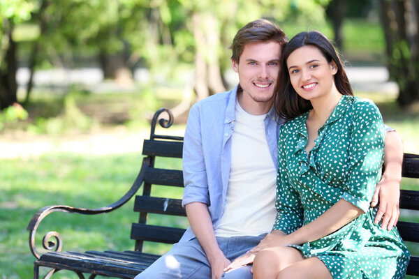 Young couple resting on bench in green park