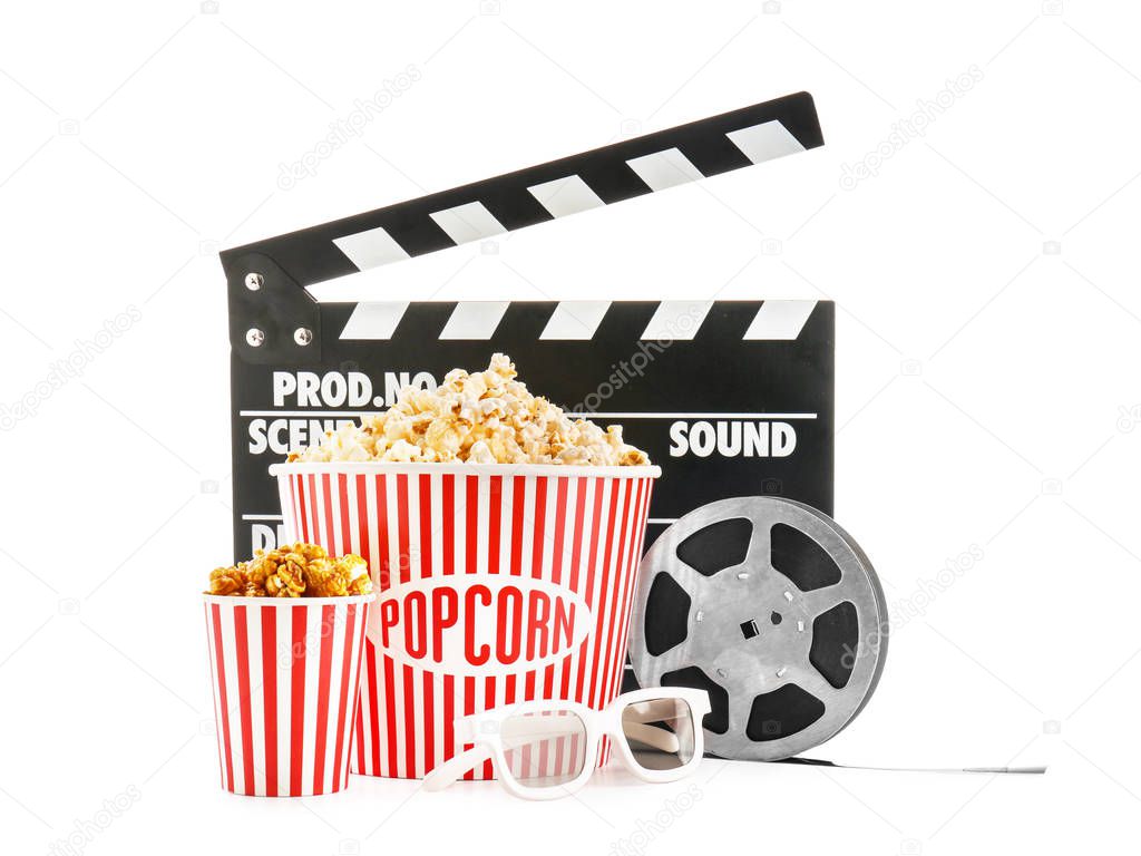 Cups with tasty popcorn, glasses, film reel and clapperboard on white background