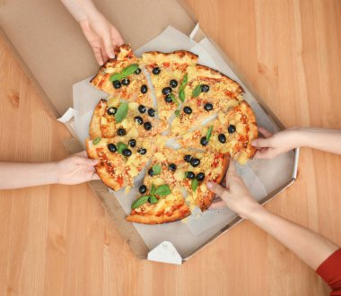 Kadın üzerindeki ahşap masa, kutusundan dilim lezzetli İtalyan pizza alarak Ana sayfa görünümü