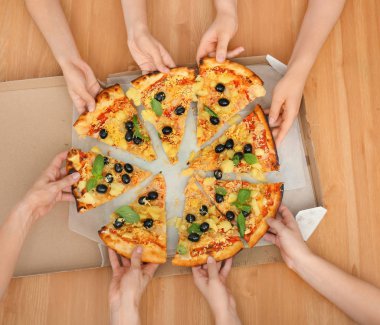 Kadın üzerindeki ahşap masa, kutusundan dilim lezzetli İtalyan pizza alarak Ana sayfa görünümü