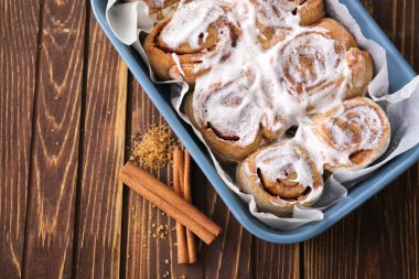 Ahşap arka plan üzerinde lezzetli tarçınlı çörek ile pişirme çanağı