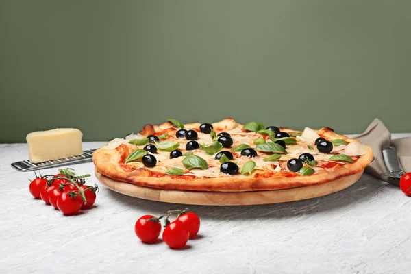 Board with delicious pizza on table against color background