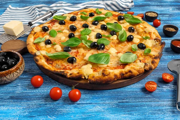 Tasty Italian pizza with olives on color wooden background