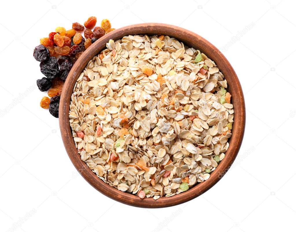 Bowl of raw oatmeal with candied fruit and raisins on white background