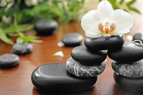 Spa stones with beautiful orchid flower on wooden table