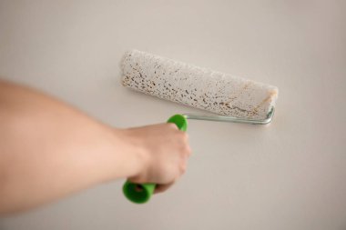 Erkek ressam rulo kapalı duvar rengini yenileme için kullanma
