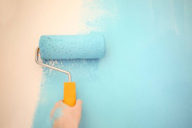 Kadın ressam rulo kapalı duvar rengini yenileme için kullanma