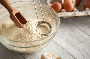 Un, kepçe ve elek masada bir kase. Ekmek Atölyesi