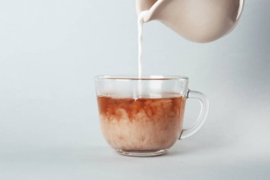 Açık renkli cam fincan çay ile içine süt dökme