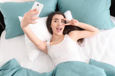 Selfie yatağa sabah alarak genç güzel kadın