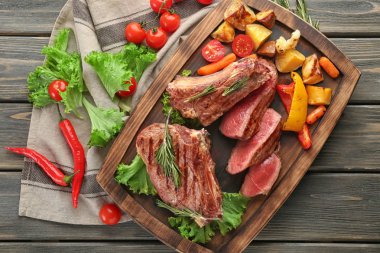 Etli biftek ve ahşap arka plan, üstten görünüm üzerinde sebze garnitür