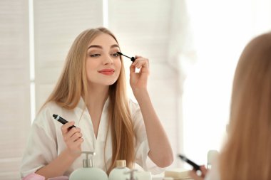 Genç kadın banyoda makyaj uygulamak
