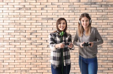 Gamepads tuğla duvar arka plan üzerinde olan genç kadın