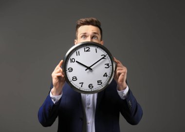 Koyu arka plan üzerinde saati ile başarılı bir iş adamı. Zaman yönetimi kavramı