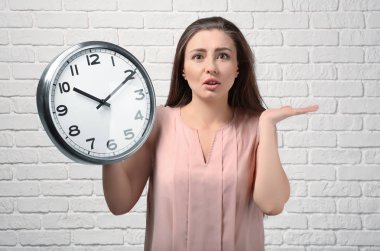 Zamana karşı beyaz tuğla duvar ile sorunlu bir kadın. Zaman yönetimi kavramı