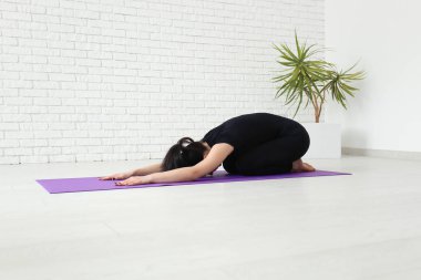 Evde yoga yapan genç bir kadın.