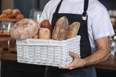 Hasır sepet taze ekmek ile dükkanda tutan erkek baker