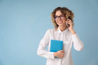 Cep telefonu tarafından renk arka plan üzerinde konuşurken resmi giysili güzel genç kadın