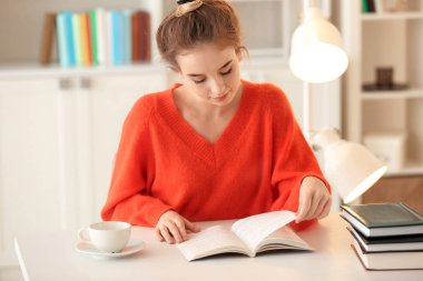 Genç kadın masasında kitap okumak