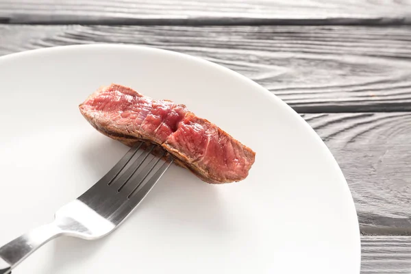Fork with delicious grilled meat on plate