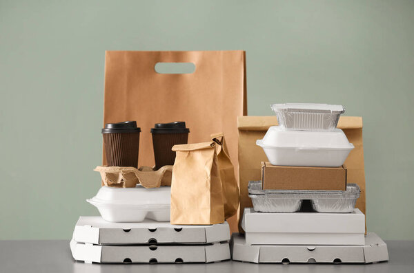 Different packages on table against color background. Food delivery service
