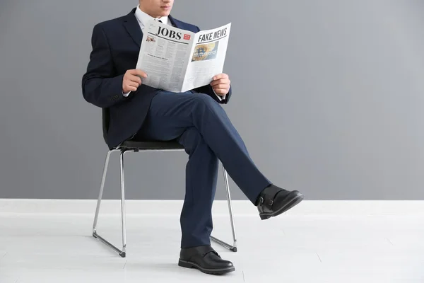 Biznesmen Siedzi Krześle Czytając Gazety Pomieszczeniu Ścianę Szary — Zdjęcie stockowe