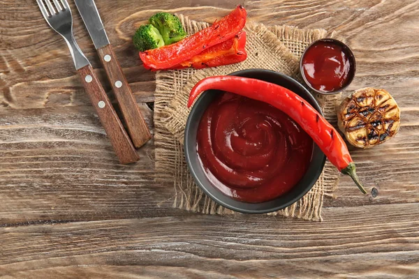 Bowl with barbecue sauce on wooden table