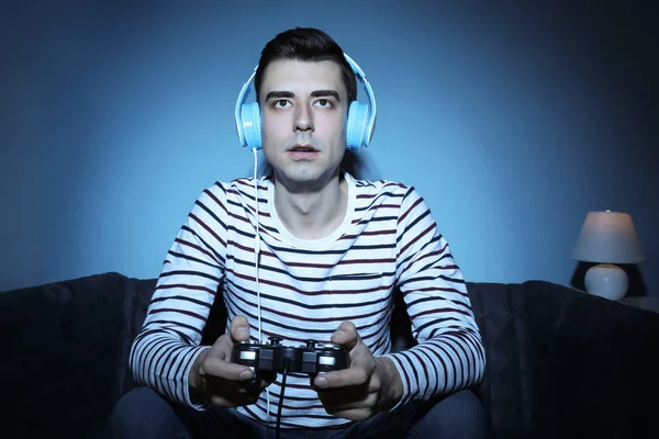 Young man playing video game at home in the evening