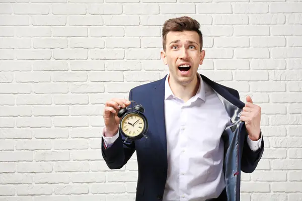 Beunruhigter Geschäftsmann Mit Wecker Gegen Weiße Backsteinmauer Zeitmanagement Konzept — Stockfoto