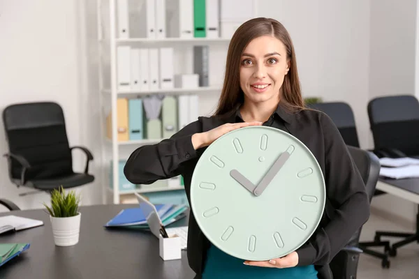 Young woman with clock in office. Time management concept