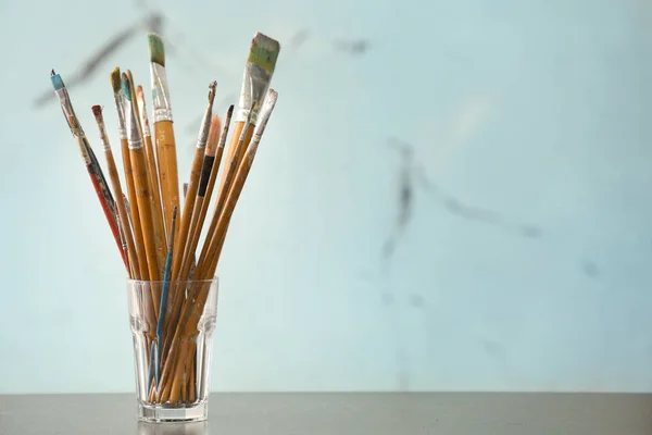 Glas Met Verf Penselen Tafel Tegen Lichte Achtergrond — Stockfoto