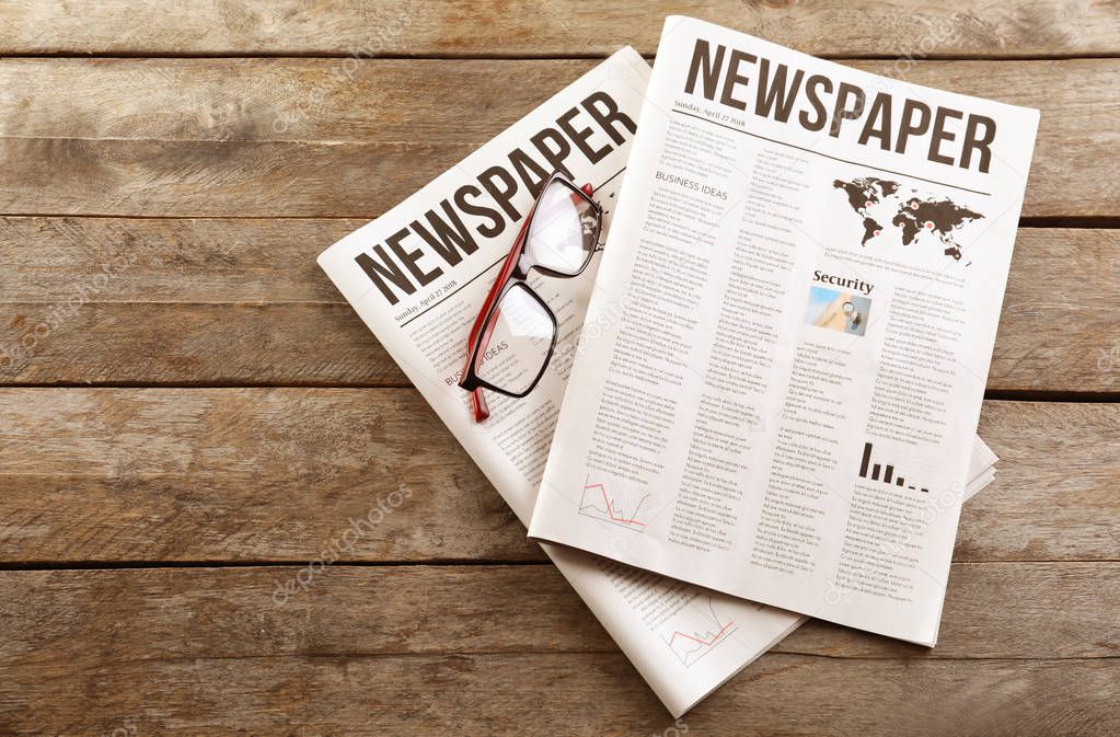 Newspapers with glasses on wooden background