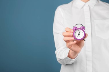 Çalar saat renk arka plan üzerinde tutan kadın. Zaman yönetimi kavramı
