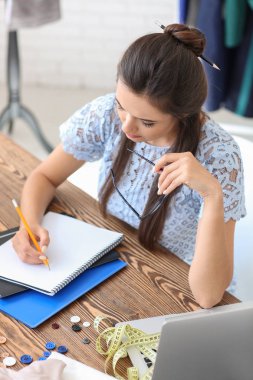 Atelier tablosunda çalışan genç kadın terzi