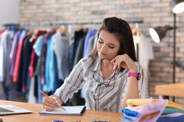Atelier tablosunda çalışan genç kadın terzi