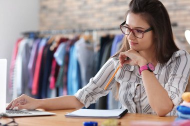 Atelier tablosunda çalışan genç kadın terzi