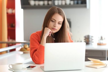 Evde dizüstü bilgisayarda çalışan serbest çalışan bir kadın.