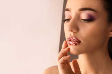 Işıklı arka planda yaratıcı makyajı olan güzel genç bir kadın.