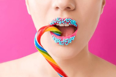 Güzel genç kadın portre renk arka plan üzerinde yaratıcı makyaj ve şeker kamışı ile