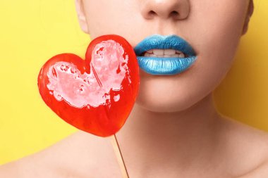 Yaratıcı makyaj ve lolipop renk arka plan, closeup üzerinde olan güzel kadın