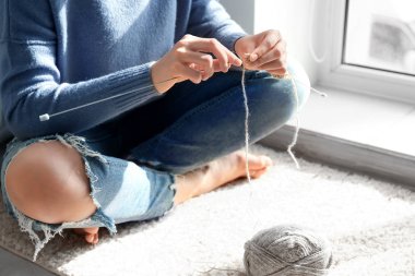 Genç kadın evde halı üzerinde elbise örgü