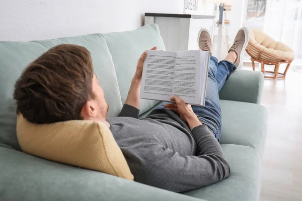 Jonge Man Leesboek Terwijl Rusten Thuis — Stockfoto