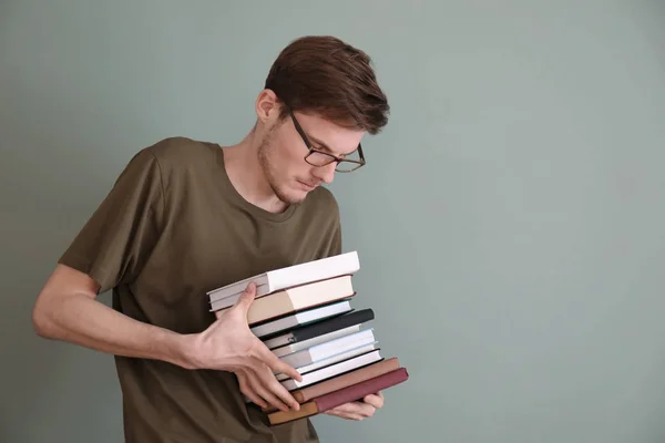 色の背景上の書籍のスタックを持つ若者 — ストック写真