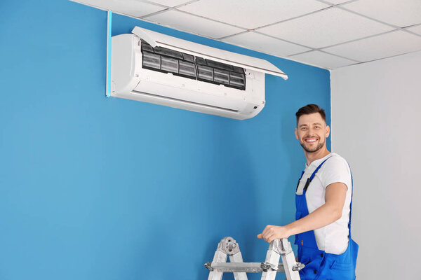 Electrician repairing air conditioner indoors