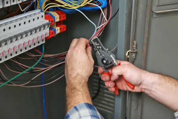 Mature electrician repairing distribution board